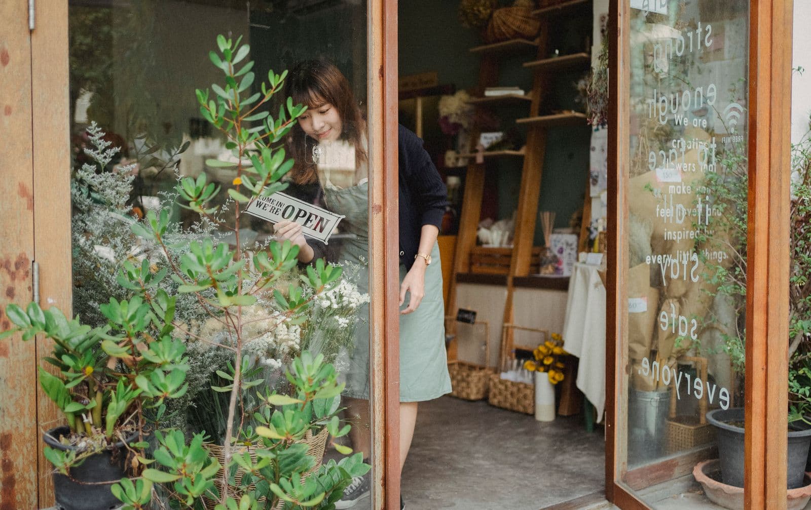 一位亞洲小型店主翻開營業招牌,準備開店
